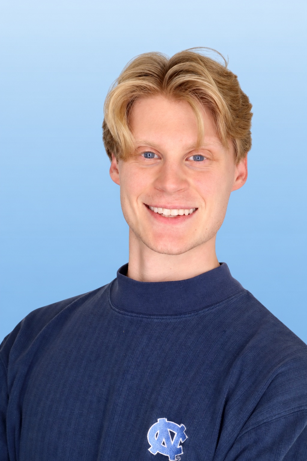 Thomas Baker smiling in a Carolina blue UNC sweatshirt
